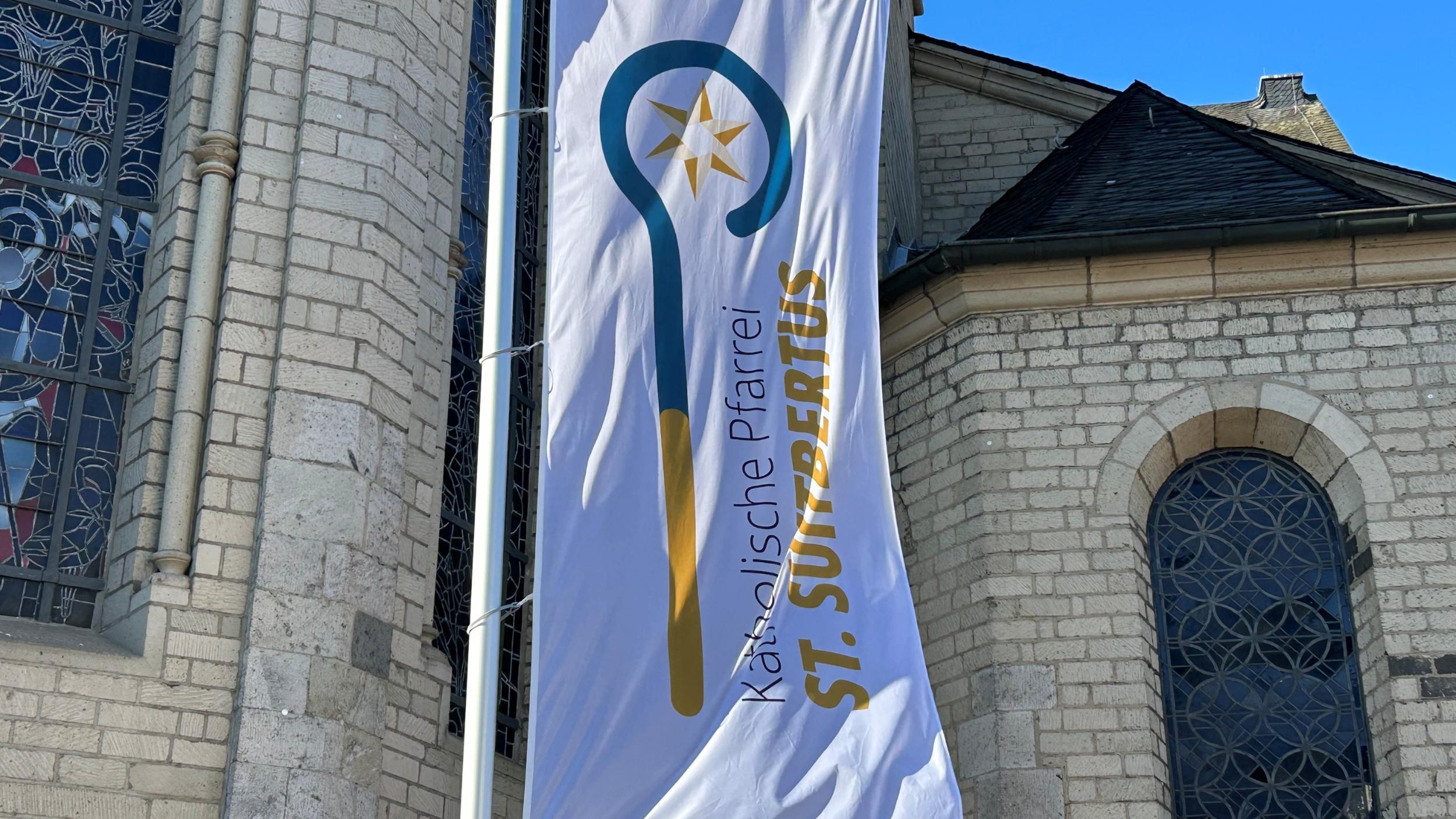 Die Flagge der Pfarrei St. Suitbertus mit dem neuen Logo vor der Basilika St. Suitbertus in Kaiserswerth