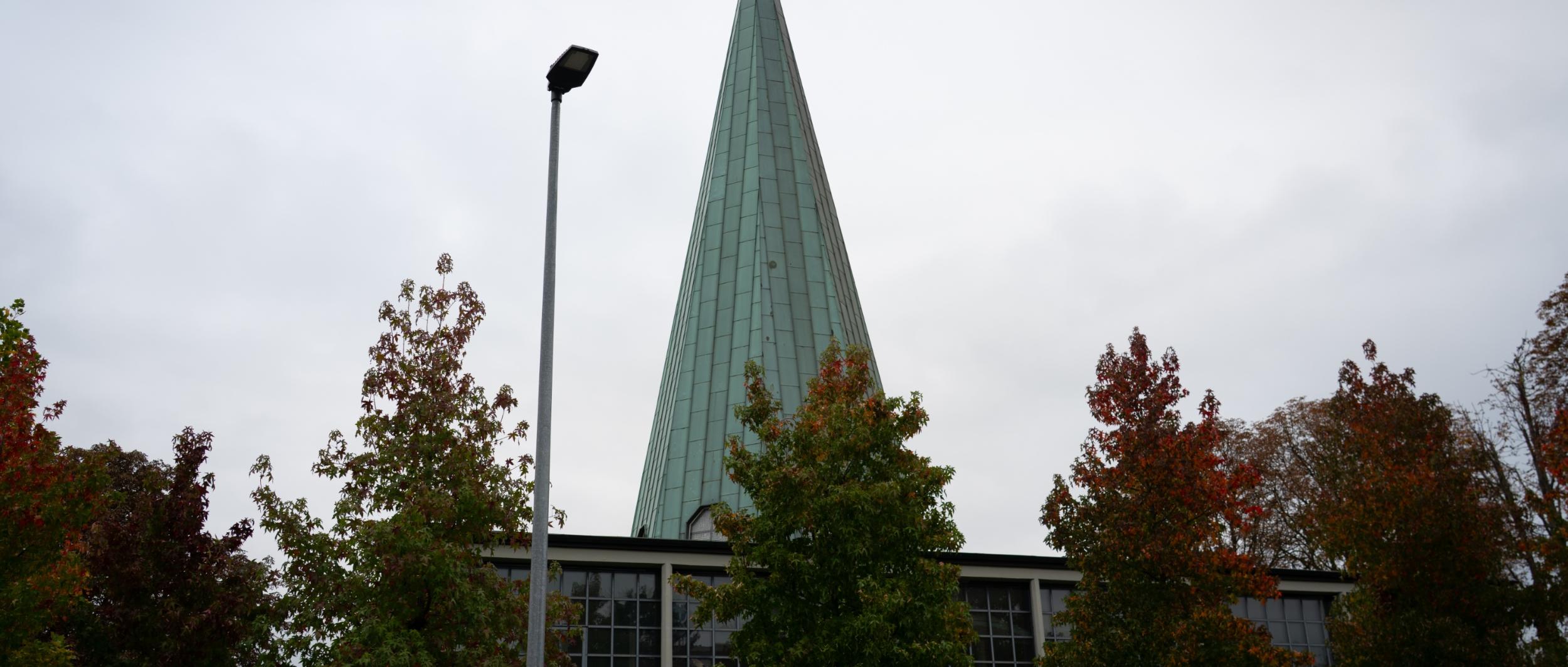 man sieht die kirche von außen mit ihrem grünen spitzen Turm