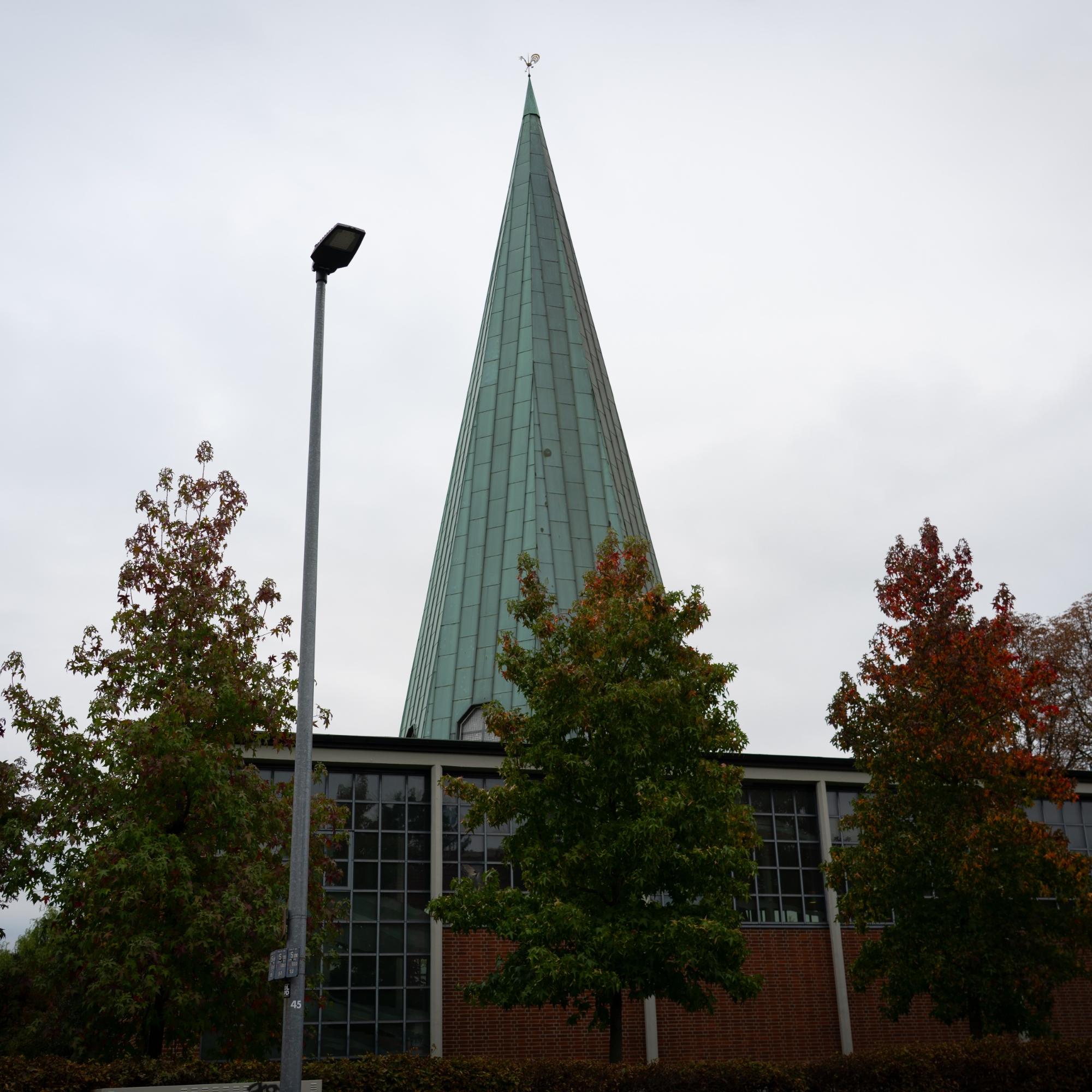 man sieht die kirche von außen mit ihrem grünen spitzen Turm