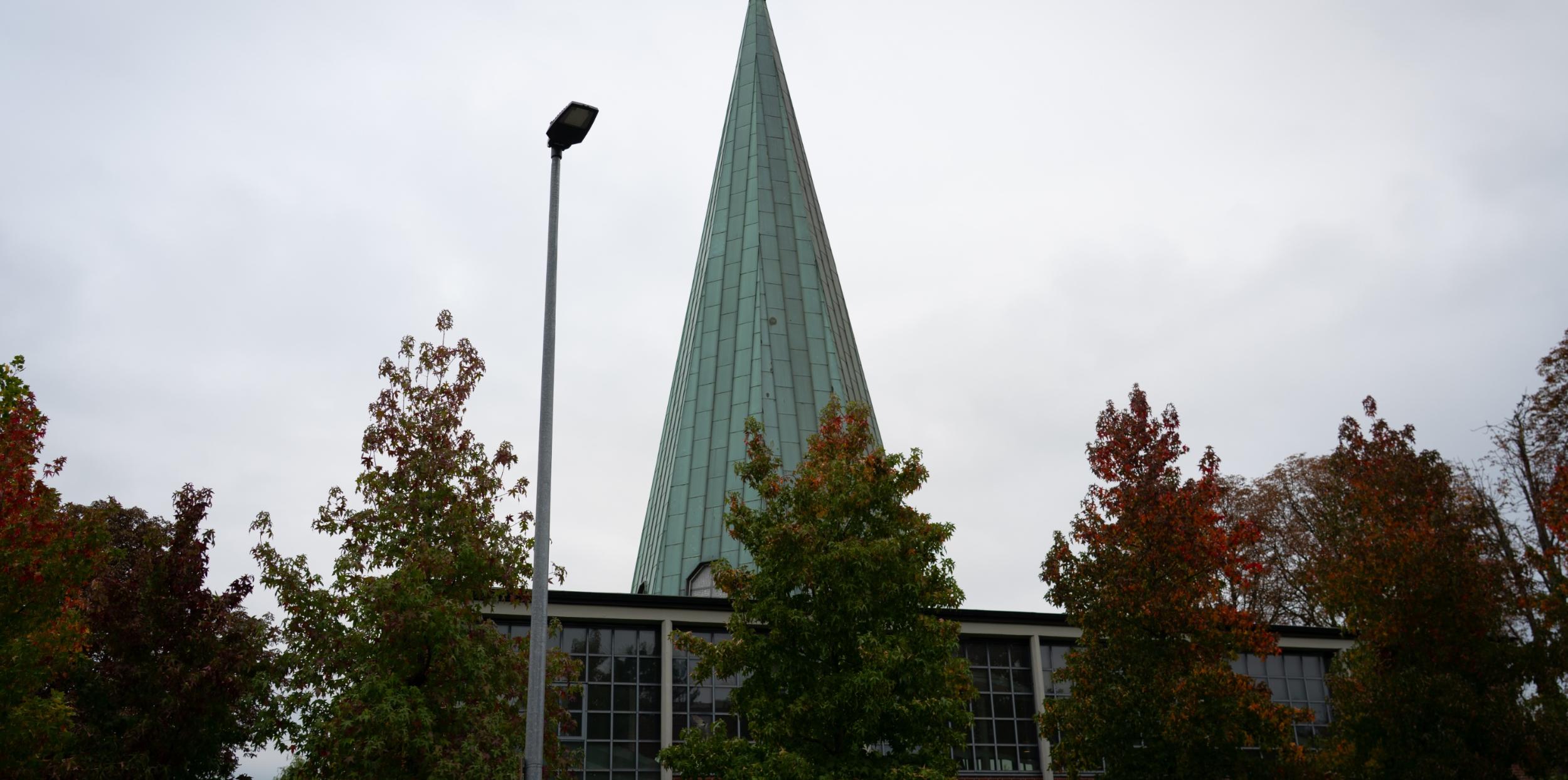 man sieht die kirche von außen mit ihrem grünen spitzen Turm
