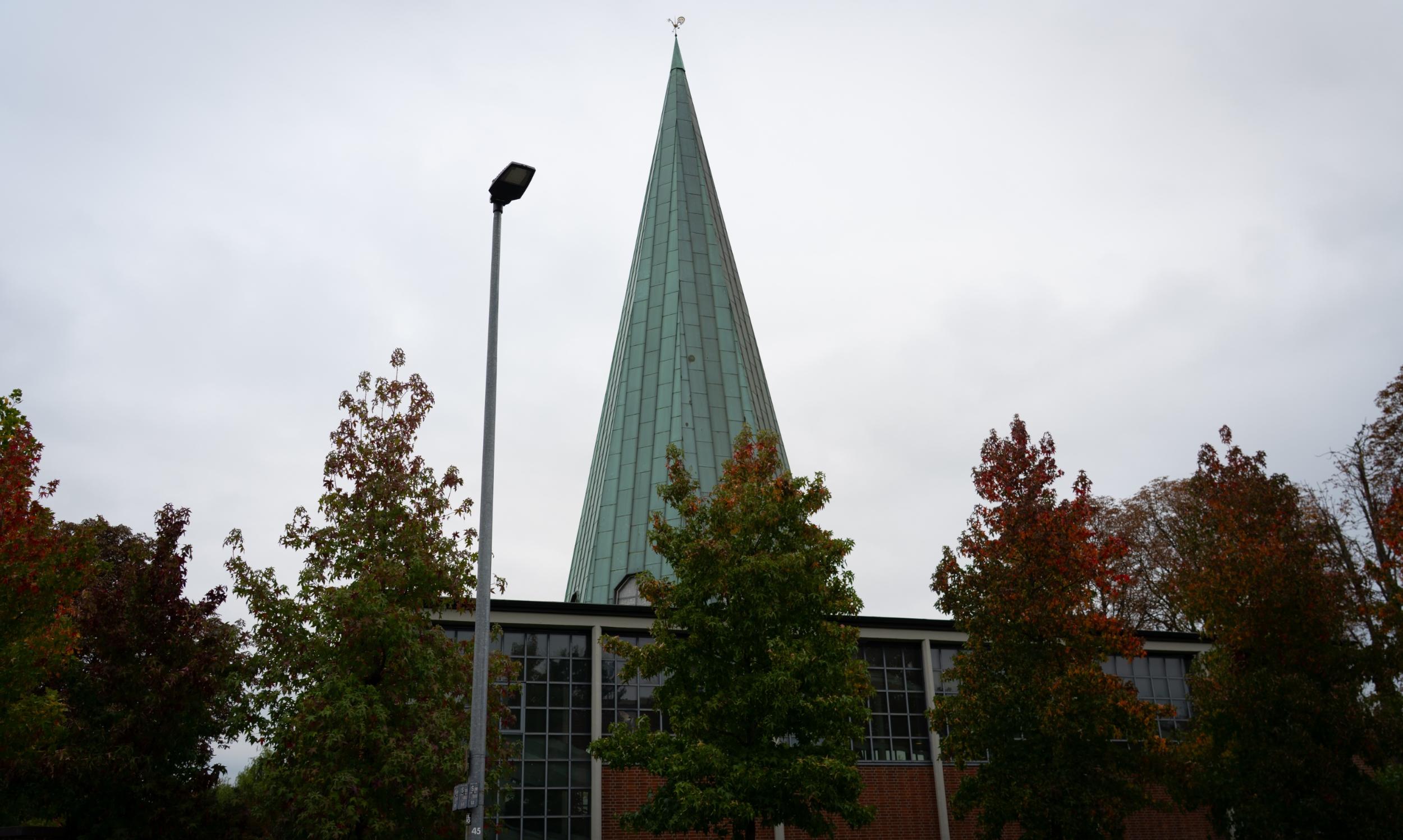man sieht die kirche von außen mit ihrem grünen spitzen Turm